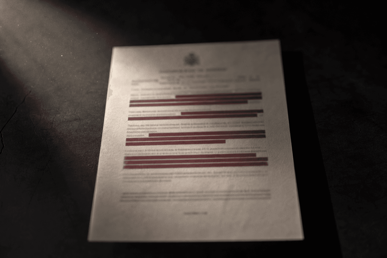 Escrito judicial sobre una mesa oscura con los datos personales tachados por barras granates